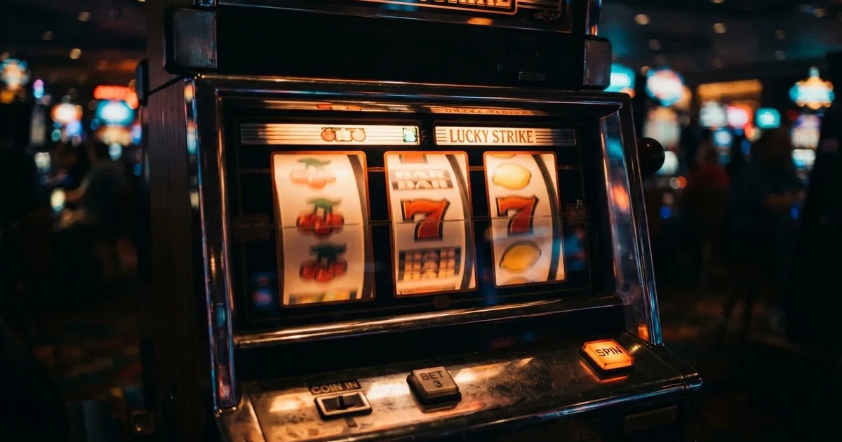 Rolos luminosos de uma slot machine numa sala escura, em grande plano — casinos online grátis em portugal